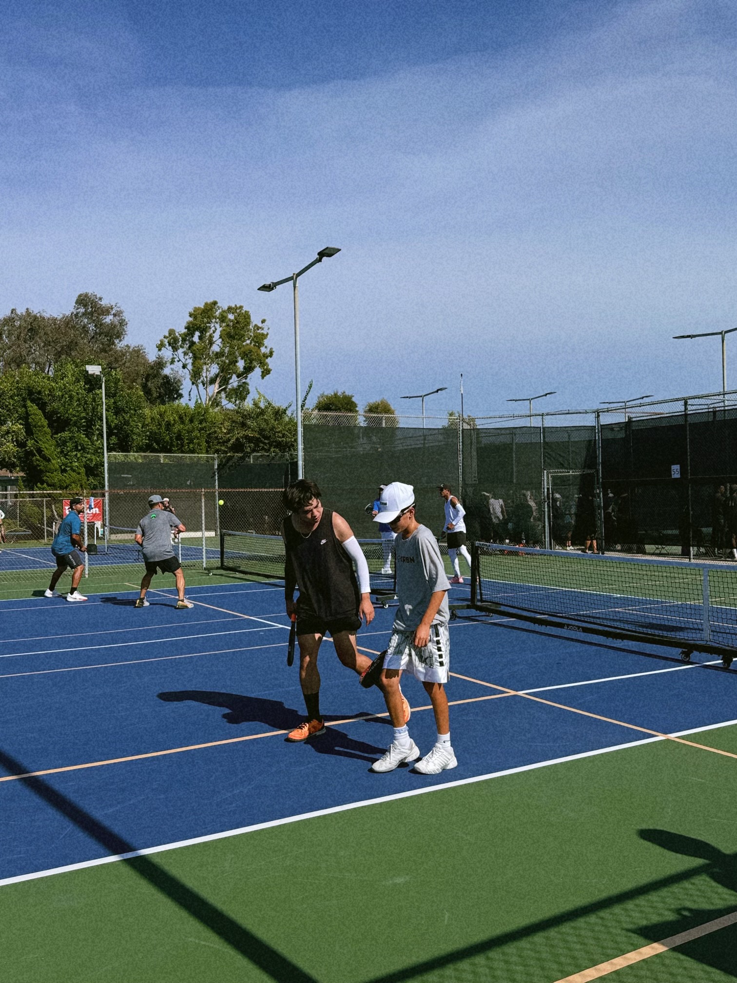 A coach walking with a young athlete during a pickleball session